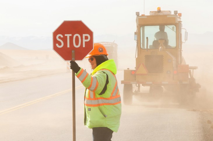 A construction worker holding a stop sign in front of a work zone. 