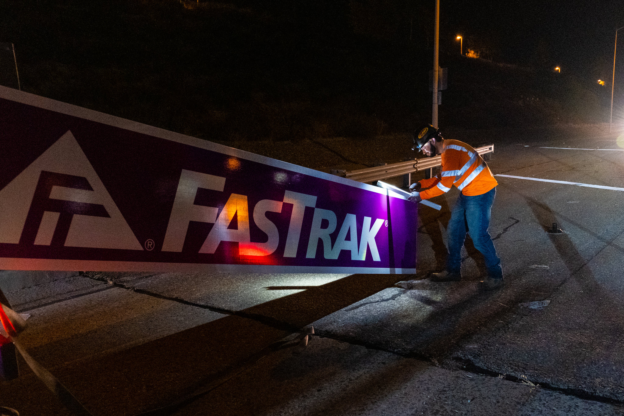 Photo of construction crews lifting a purple FasTrak sign. 
