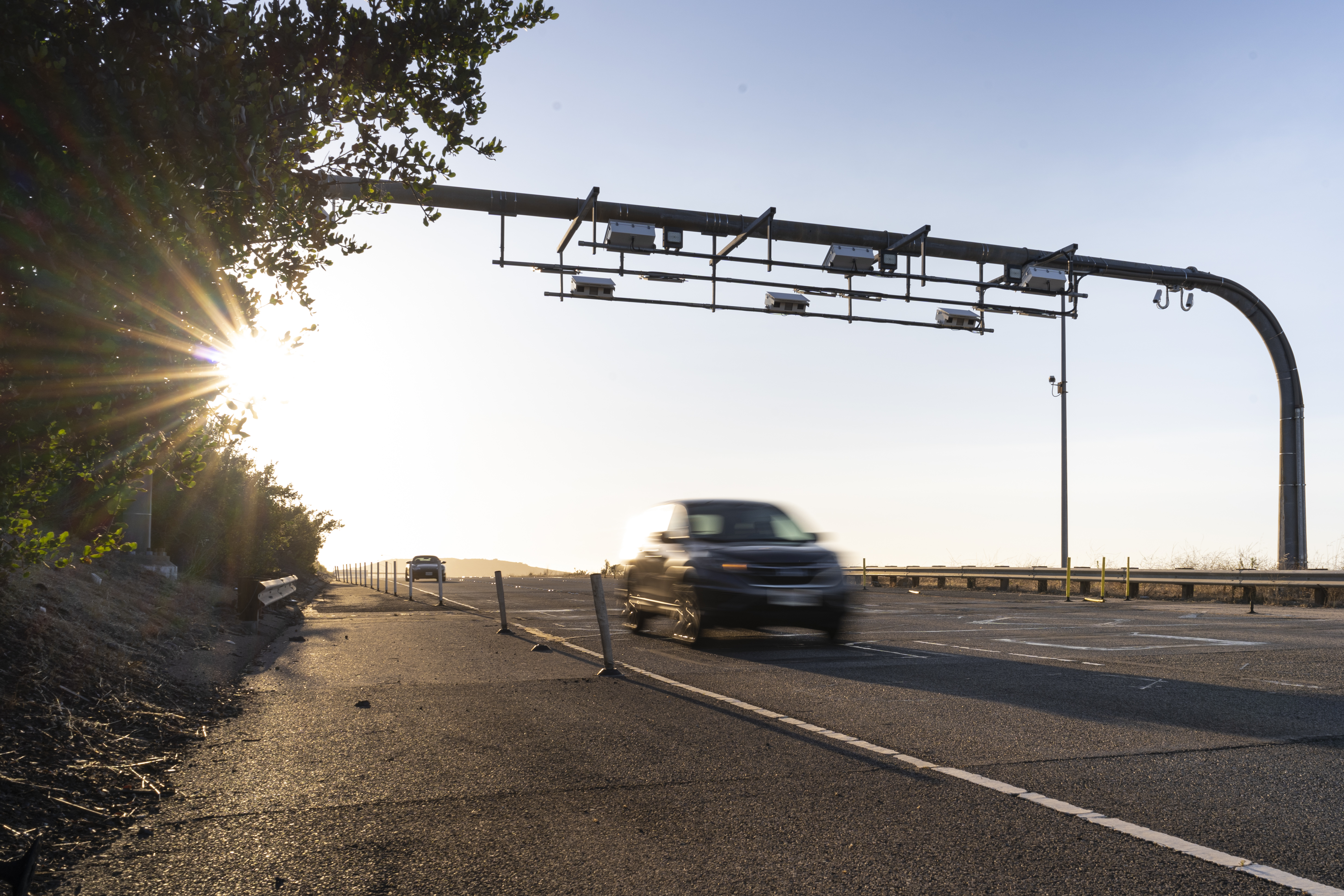 Image of a car driving through a toll point. 