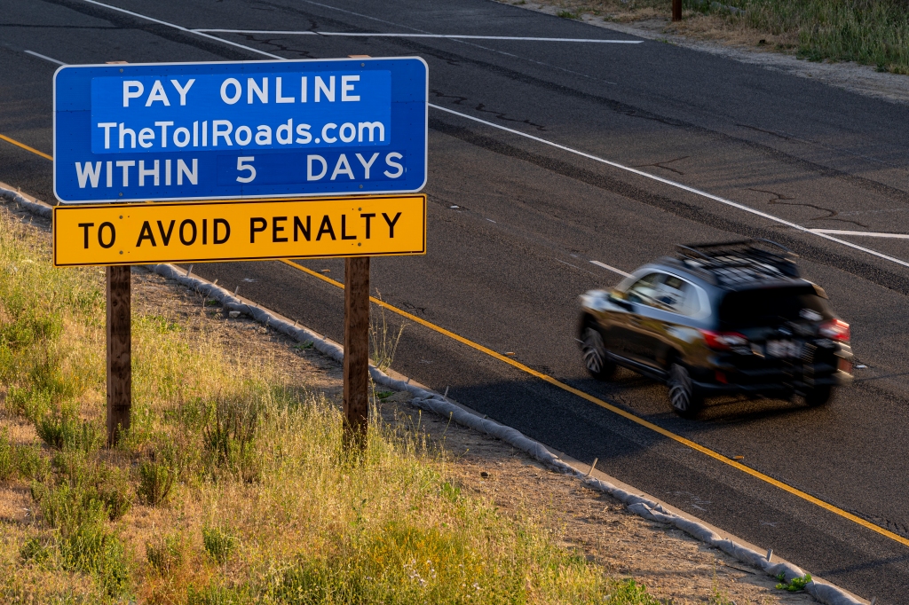 Photo of a car passing a blue sign on The Toll Roads that reads "Pay Online TheTollRoads.com Within 5 Days to avoid penalty" 