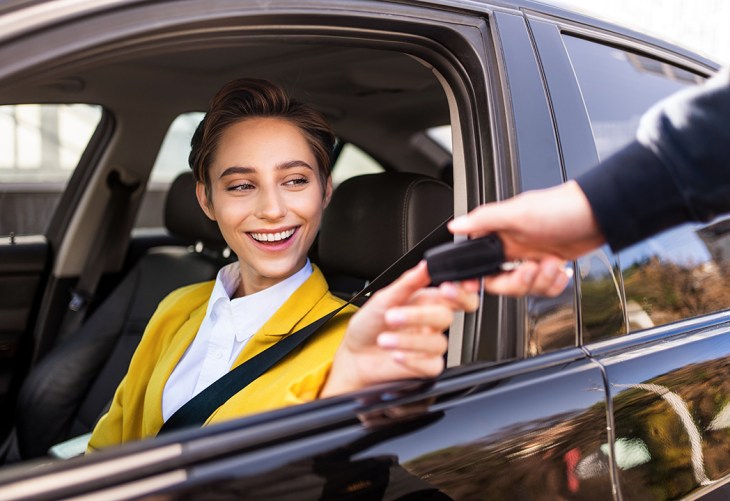 person receiving a car key while sitting in a car