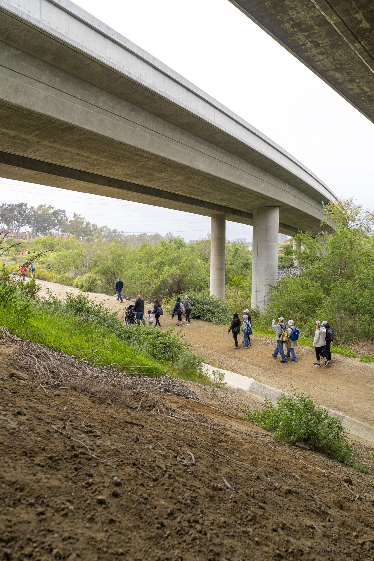 Hikers walking along a trail under a roadway